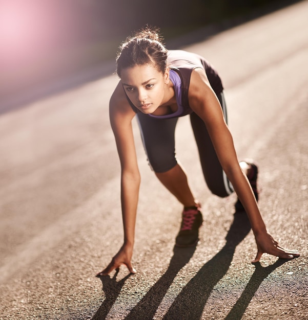 Photo le corps réalise ce que l'esprit croit plan d'une jeune femme en position de départ pour une course