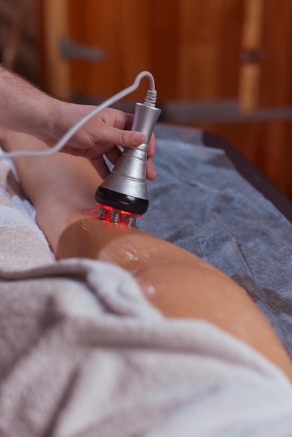 Correction de la figure matérielle Cosmétologie machine Belle femme ayant une procédure de cavitation enlevant la cellulite sur ses fesses