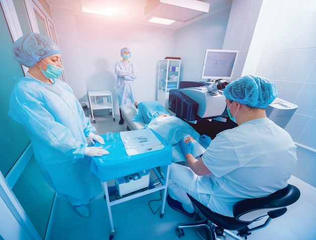 Correction de la vue au laser. Un patient et une équipe de chirurgiens en salle d'opération lors d'une chirurgie ophtalmique.