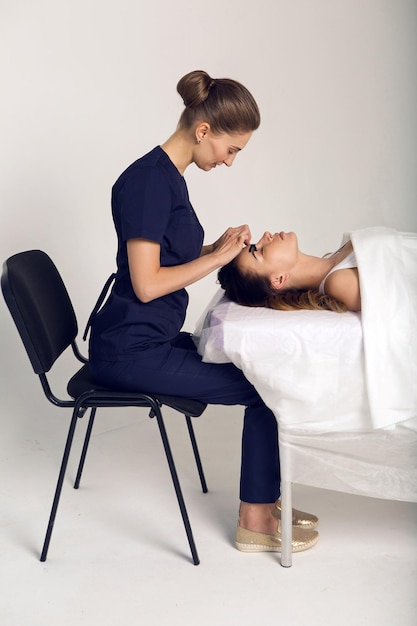 Photo cosméticienne faisant l'enregistrement du visage du patient allongé sur le bureau dans le bureau