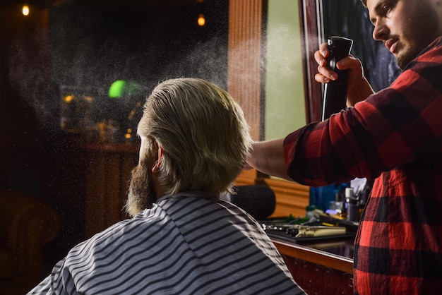 Cosmétique pour hommes Coiffeur servant le client au salon de coiffure Coiffeur styliste personnel rétro et vintage Concevoir des outils de coiffure pour la coupe de cheveux dans le salon de coiffure beau coiffeur coupant les cheveux du client