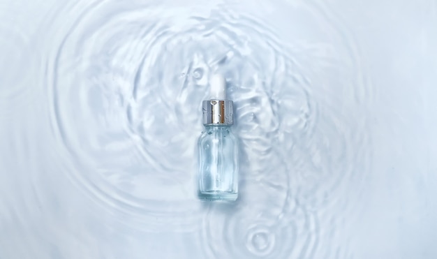 Cosmétiques dans une bouteille dans l'eau, concept d'hydratation de la peau. Acide hyaluronique. Mise au point sélective. La nature.