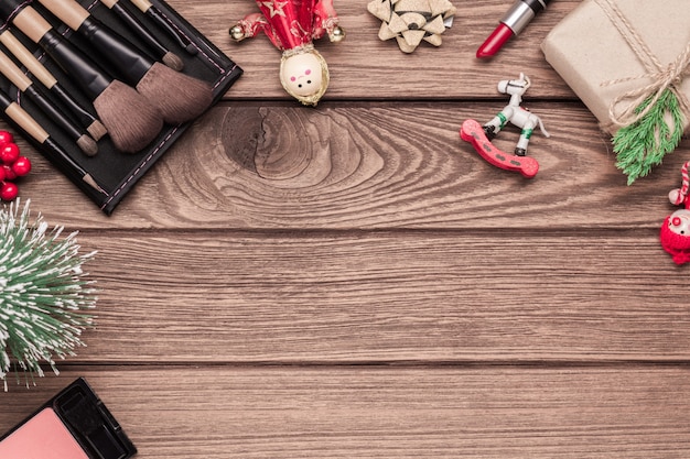 Cosmétiques femme, pinceaux de maquillage, rouge à lèvres et ornements de Noël sur bois