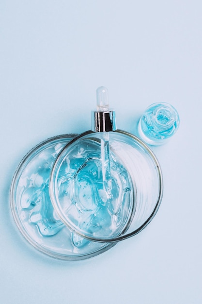 Cosmétiques gel liquide sérum lubrifiant acide hyaluronique avec des bulles d'oxygène de fond bleu de verrerie de laboratoire en verre