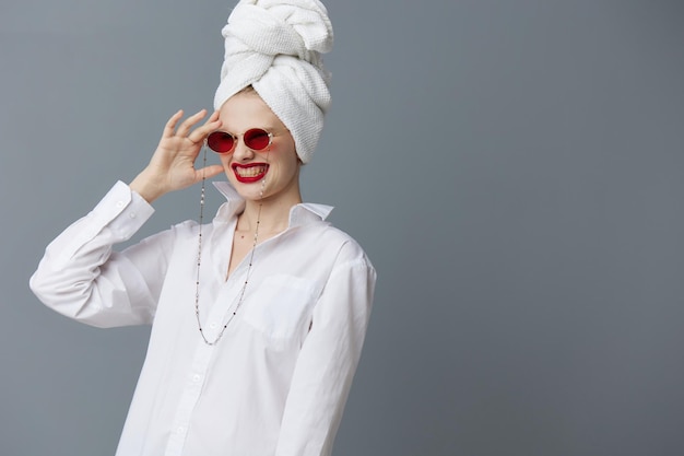 Cosmétiques de lunettes de soleil rouge femme glamour avec une serviette sur la tête fond gris