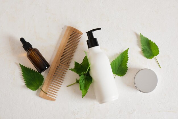 Photo cosmétiques naturels avec extrait d'ortie, concept de soins de la peau et des cheveux, feuilles d'ortie fraîches et bouteilles de maquette