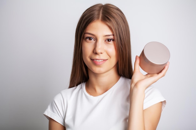 Cosmétiques de peau de visage de femme, jolie femme tenir dans la crème faciale de main.