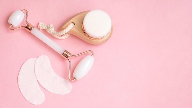 Cosmétiques à plat avec espace de copie Masseur à rouleaux pour le visage et patchs sous les yeux sur un rose