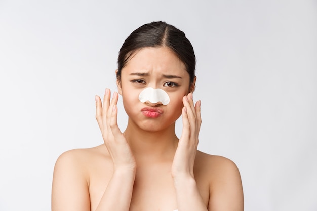 Cosmétologie. Portrait de beau modèle féminin asiatique avec masque sur le nez. Gros plan d'une jeune femme en bonne santé avec une peau douce et pure et un maquillage naturel frais.