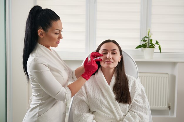 Cosmetologist faisant l'injection dans la procédure de biorevitalisation de plan rapproché de visage féminin