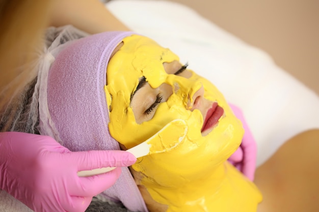 Cosmétologue appliquer un masque facial dans un salon de beauté.