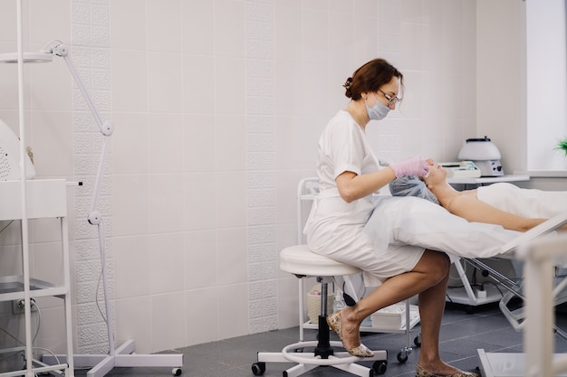 Le cosmétologue au bureau fait des procédures à la fille