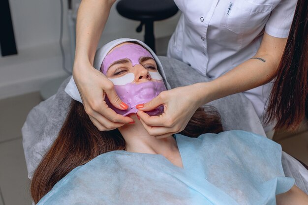 Le cosmétologue enlève un masque dur du visage d'un jeune client pour terminer la procédure de spa.