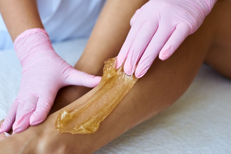Cosmétologue épilation les jambes d'une femme