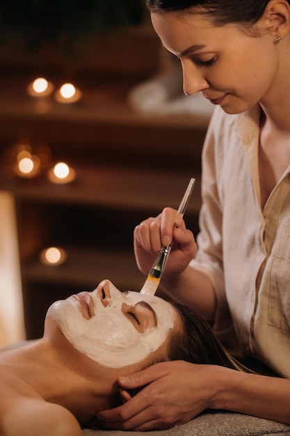 Un cosmétologue fabrique un masque pour le visage d'une femme pour rajeunir la peau