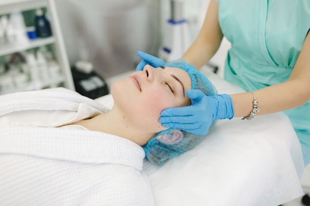 Cosmétologue faire un massage du visage dans un salon de beauté