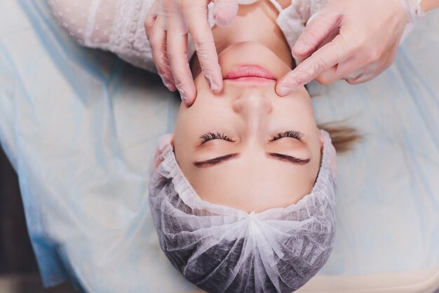 le cosmétologue fait un massage buccal des muscles faciaux du patient