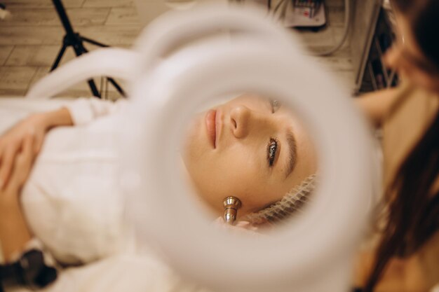 Le cosmétologue fait la procédure Microdermabrasion de la peau du visage d'une belle jeune femme dans un salon de beautéCosmétologie et soins professionnels de la peau