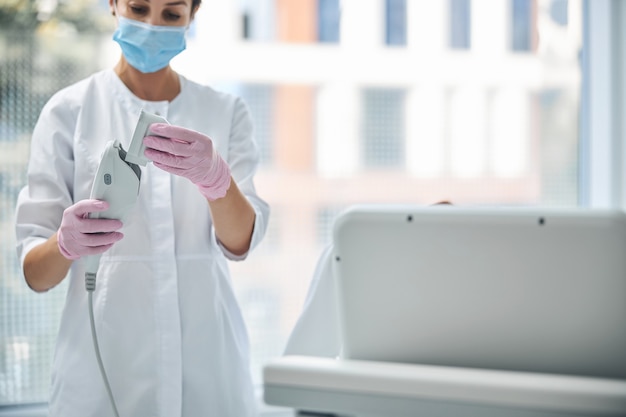 Photo cosmétologue féminine caucasienne qualifiée ciblée se préparant à effectuer une procédure cosmétique dans un salon de beauté