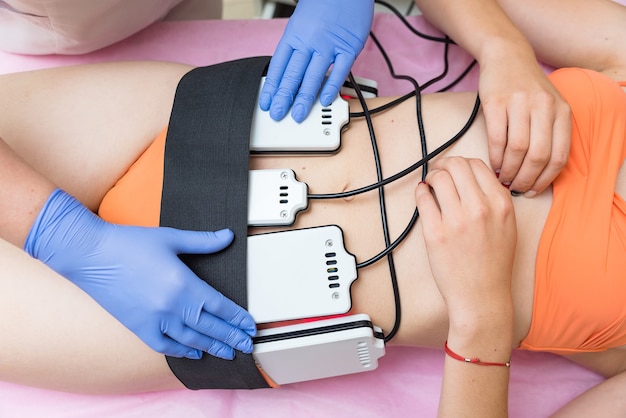 Photo le cosmétologue installe la machine de massage sur le client