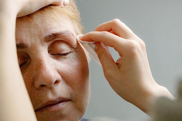 Photo une cosmétologue peint les sourcils d'une femme âgée