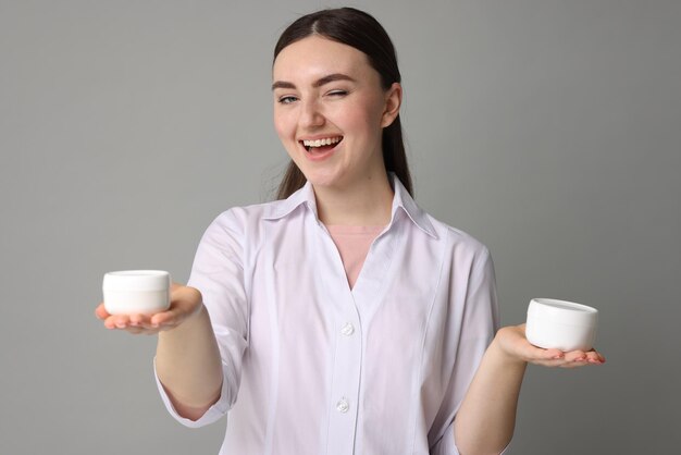 Cosmétologue avec des produits cosmétiques sur fond gris