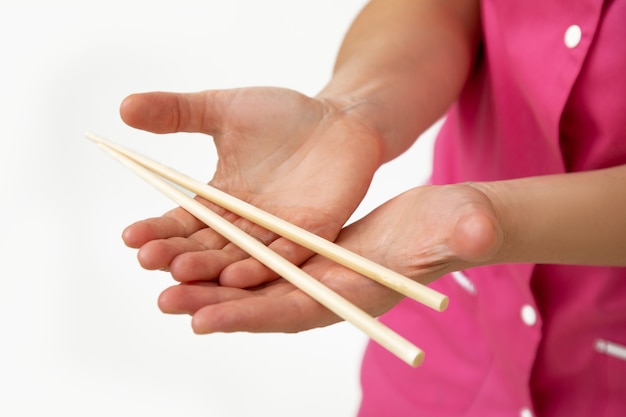 Un cosmétologue en uniforme médical rose tient des bâtons de massage en bambou dans ses mains. Petite entreprise. Salon SPA. Industrie de la beauté. Procédures anti-âge. Soins de massage. Mode de vie.