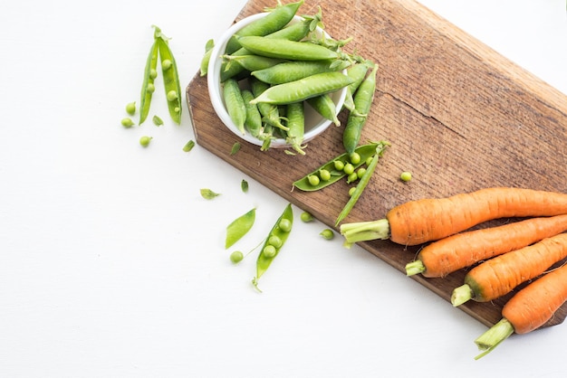 Une cosse de pois et de carotte sur planche de bois