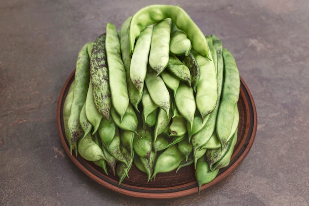 Cosses de haricots verts sur une plaque d'argile