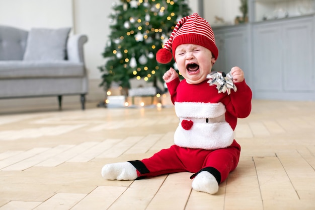 Costume de bébé en Cristmas pleurant sur le sol