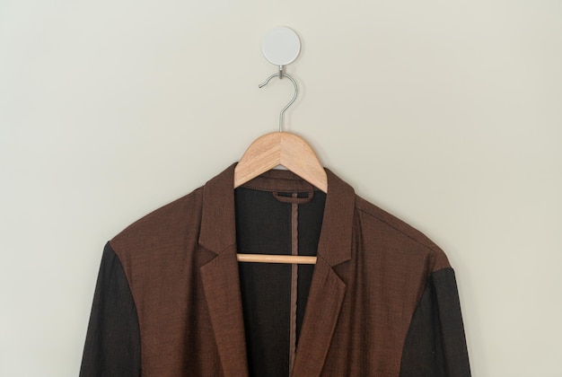 costume marron foncé suspendu avec un cintre en bois sur le mur