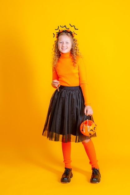 costume de sorcière adolescente sur fond jaune tenant des vers de marmelade de citrouille confent halloween