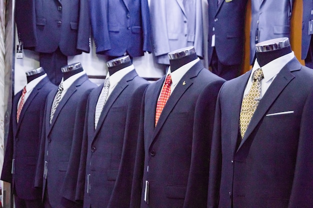 Des costumes pour hommes de style classique sur mannequins sont exposés à la vente dans une boutique à la mode de vêtements modernes