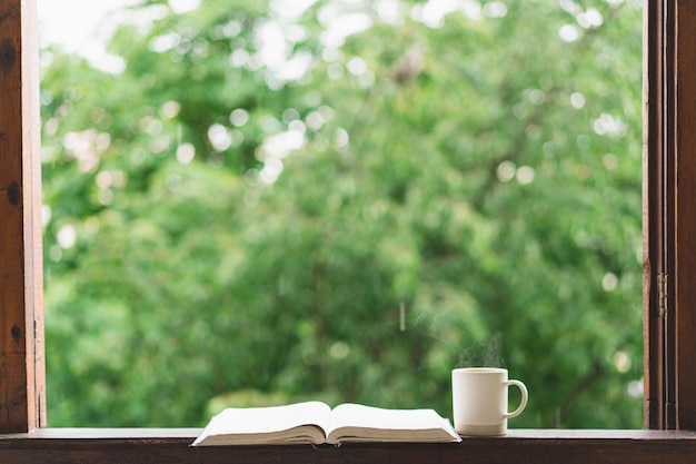 Cosy summer still life tasse de thé chaud et livre ouvert sur le rebord de la fenêtre vintage et la pluie à l'extérieur de l'appartement Pluie en été