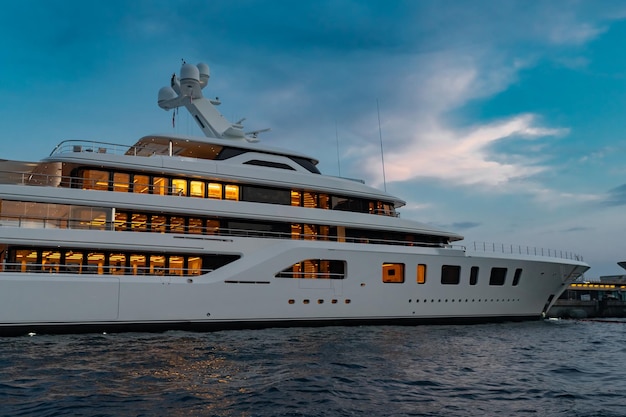 Le côté droit d'un immense yacht dans le port de monaco au coucher du soleil, l'éclairage intérieur est à bord brillant de...