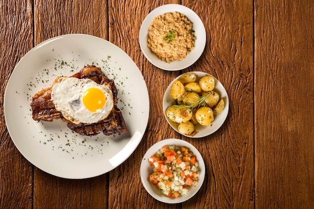 Côte de porc aux oeufs et bacon, accompagnée de pommes de terre rustiques, vinaigrette et farine de maïs