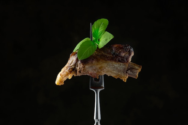 Côte de porc grillée avec des feuilles de basilic sur une fourchette à viande