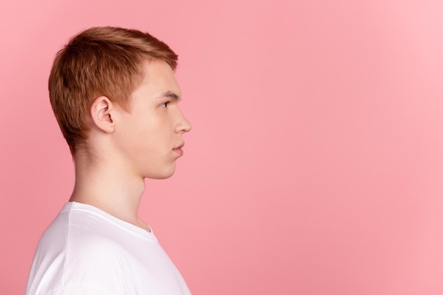 Côté profil photo de jeune homme sérieux look intelligent espace vide cheveux roux isolé sur fond de couleur rose