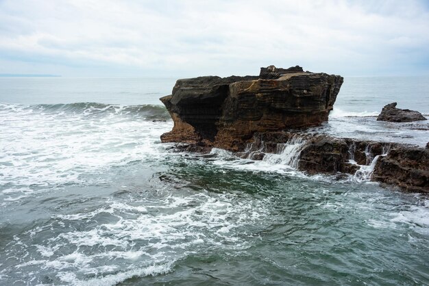 Photo côte rocheuse de la mer frappée par les vagues sur l'île de bali