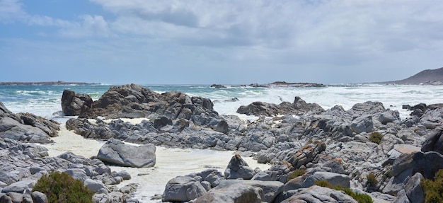 Une côte rocheuse sur une plage du Cap avec des nuages couverts Un rivage avec des rochers à l'océan avec quelques vagues Côte rocheuse de la mer de montagne avec une journée froide au bord d'une piscine rocheuse