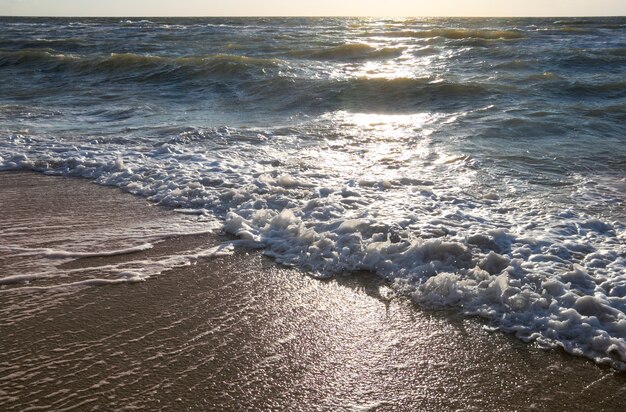 Côte, surf et chemin du soleil du soir sur la surface de l'eau de mer