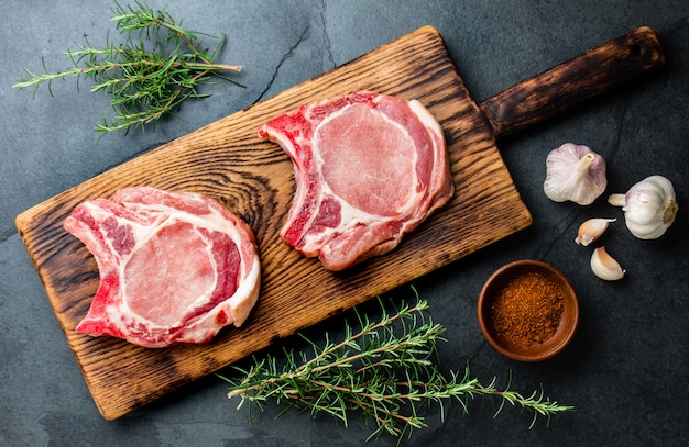 Côtelette de porc cru aux herbes sur planche de bois