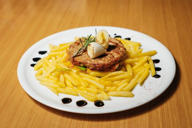 Côtelette de porc, pâtes, poireaux, romarin sur une assiette blanche.