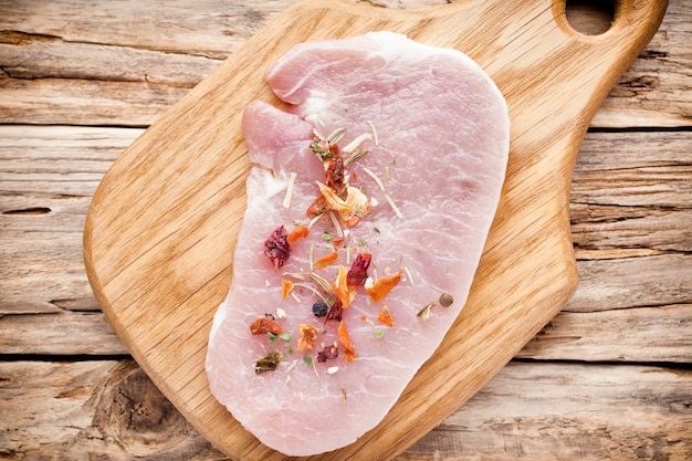 Photo côtelette de porc, tranches de viande sur fond de bois.