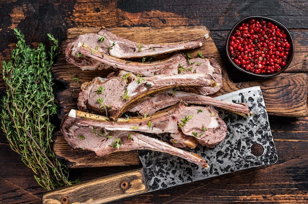 Côtelettes D'agneau Grillées Au Barbecue Côtelettes De Bifteck Sur Planche De Boucher Avec Couperet à Viande. Fond En Bois Foncé. Vue De Dessus.