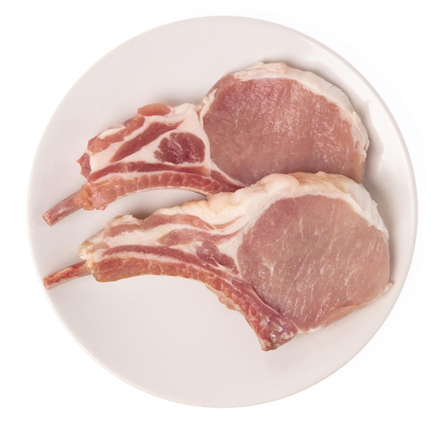 Photo côtelettes de porc crues sur plaque isolé sur fond blanc