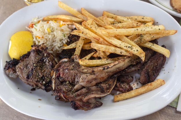 Côtes d'agneau et frites dans une assiette sur une table dans un restaurant en plein air de rue