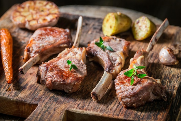 Côtes d'agneau rôties épicées aux légumes sur une vieille planche de bois