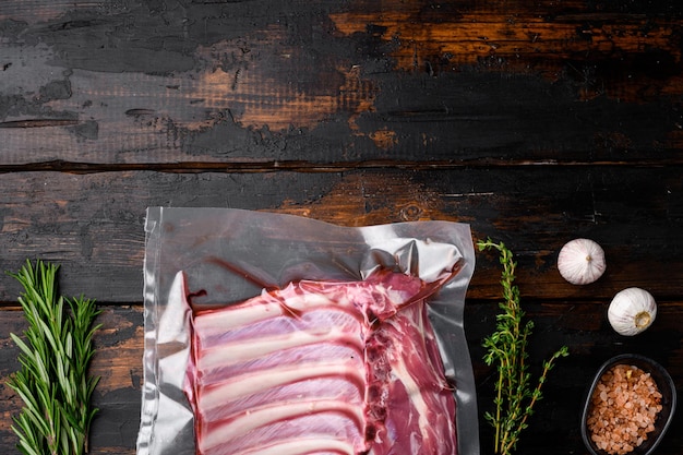 Côtes d'agneau viande fraîche Ensemble scellé sous vide, sur fond de table en bois foncé ancien, vue de dessus à plat, avec espace de copie pour le texte