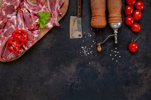 Côtes et assaisonnements de viande d'agneau fraîche crue sur une surface sombre